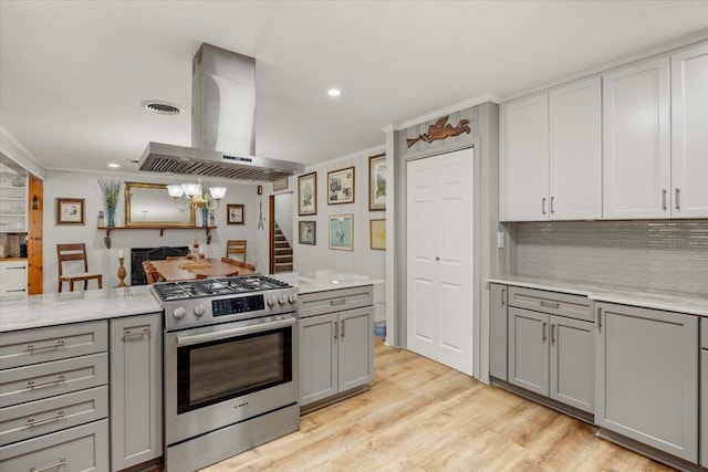 kitchen featuring gray cabinetry, island range hood, high end range, and ornamental molding