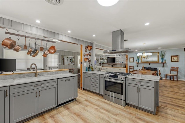 kitchen with island exhaust hood, stainless steel range, gray cabinets, and sink