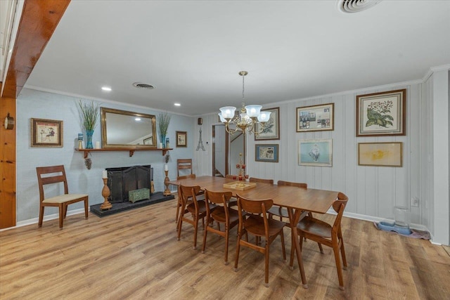 dining space with light wood-type flooring, an inviting chandelier, and crown molding