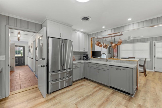 kitchen featuring kitchen peninsula, stainless steel fridge, gray cabinetry, crown molding, and light hardwood / wood-style flooring