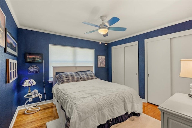 bedroom with ceiling fan, light wood-type flooring, ornamental molding, and two closets