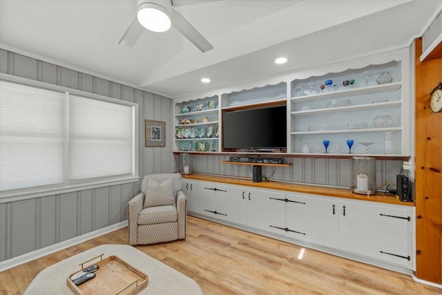sitting room featuring ceiling fan, light wood-type flooring, built in features, and vaulted ceiling