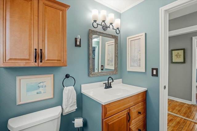 bathroom featuring wood-type flooring, vanity, toilet, and ornamental molding