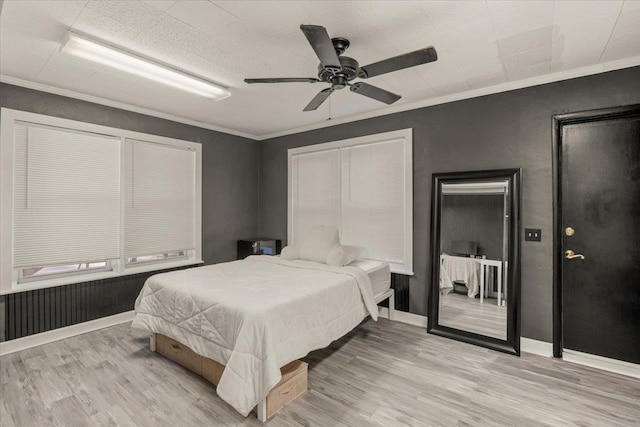 bedroom featuring light wood-type flooring, ceiling fan, and crown molding