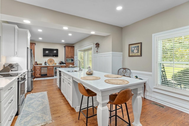 1244 Salem Rd, Havana, FL 32333 - kitchen with appliances with stainless steel finishes, a sink, light countertops, a wainscoted wall, and a breakfast bar