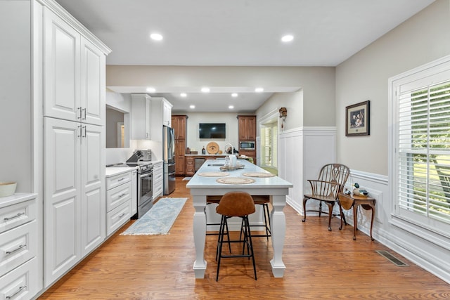 1244 Salem Rd, Havana, FL 32333 - kitchen featuring appliances with stainless steel finishes, light countertops, a breakfast bar, a wainscoted wall, and a center island