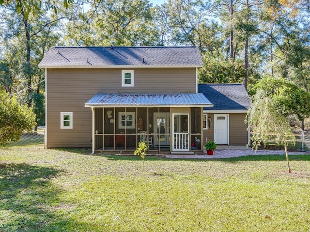 back of property with a lawn, a patio area, and a sunroom