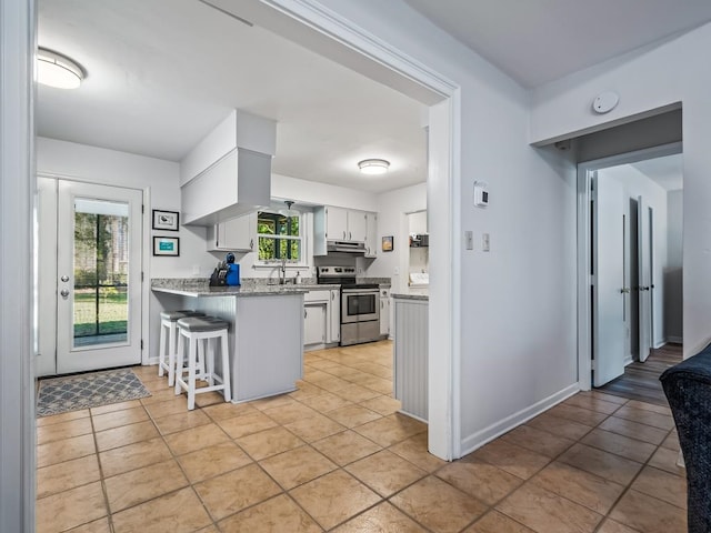 kitchen with light stone countertops, a breakfast bar, sink, white cabinets, and stainless steel electric range oven