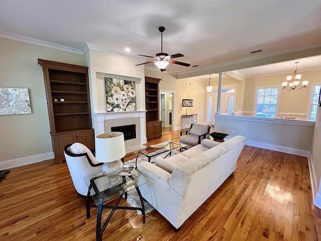 2541 Lagrange Trl, Tallahassee, FL 32312 - living room with crown molding, wood finished floors, ceiling fan, a tiled fireplace, and a chandelier