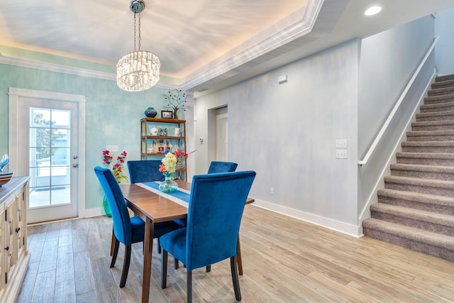 dining room featuring a raised ceiling, crown molding, a notable chandelier, and light wood-type flooring