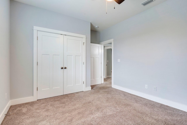 unfurnished bedroom featuring light carpet, ceiling fan, and a closet