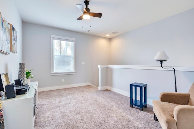 living area featuring light carpet and ceiling fan