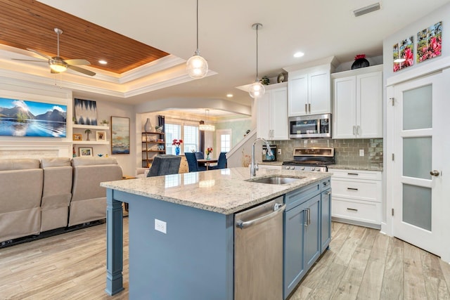 kitchen with white cabinetry, sink, a kitchen island with sink, stainless steel appliances, and a raised ceiling