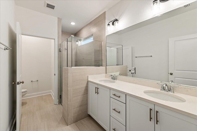 bathroom with vanity, toilet, and a shower with door