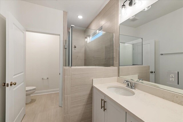 bathroom with toilet, vanity, and a tile shower