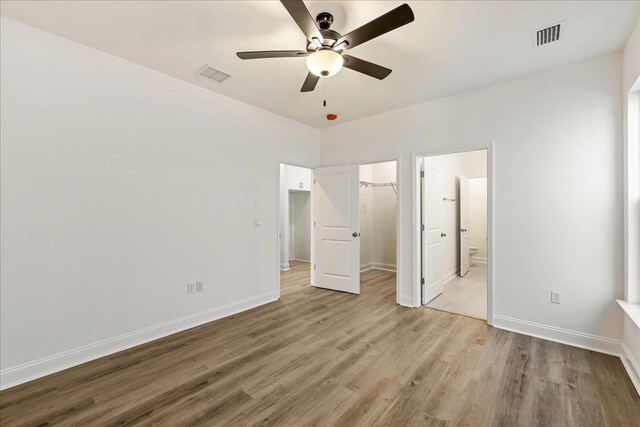 unfurnished bedroom with ensuite bathroom, light hardwood / wood-style floors, and ceiling fan