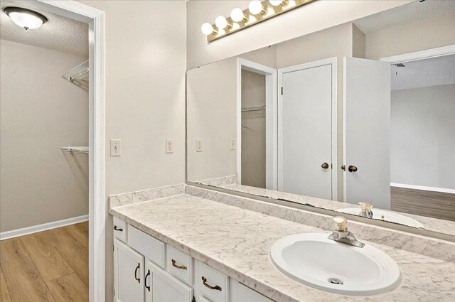 1538 Mclawrence Way, Tallahassee, FL 32317 - bathroom featuring vanity, wood finished floors, a spacious closet, a textured ceiling, and baseboards