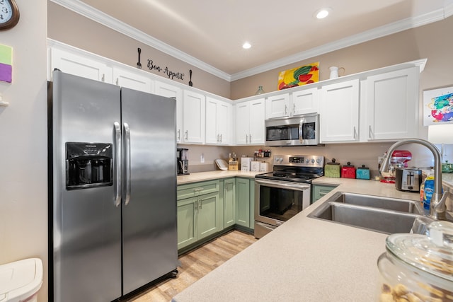 kitchen with a sink, white cabinetry, green cabinets, light countertops, and appliances with stainless steel finishes