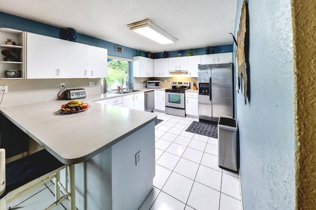 kitchen featuring kitchen peninsula, a kitchen breakfast bar, a textured ceiling, stainless steel appliances, and white cabinets