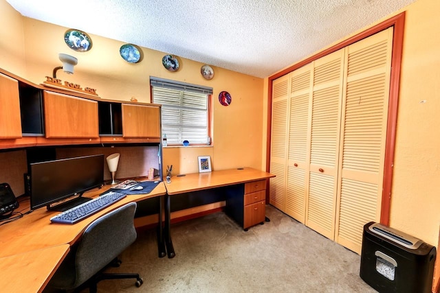 office featuring built in desk, a textured ceiling, and light carpet