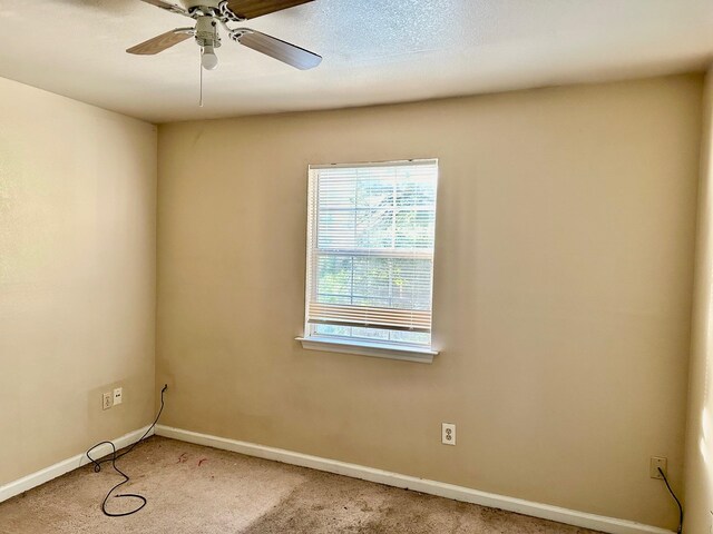 empty room with ceiling fan, a textured ceiling, and carpet