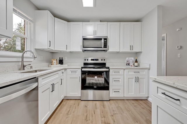 kitchen featuring sink, light stone counters, white cabinets, and stainless steel appliances