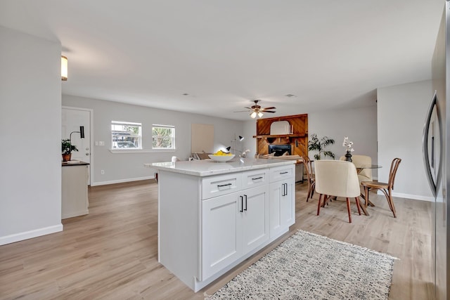 kitchen featuring light wood-type flooring, white cabinetry, a center island, and ceiling fan