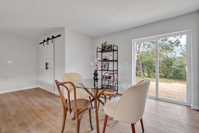 dining area with light hardwood / wood-style floors and a barn door