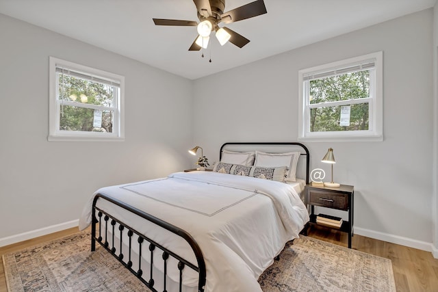 bedroom with multiple windows, ceiling fan, and light hardwood / wood-style floors