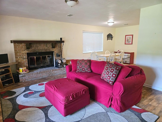 living area featuring visible vents, baseboards, wood finished floors, and a fireplace