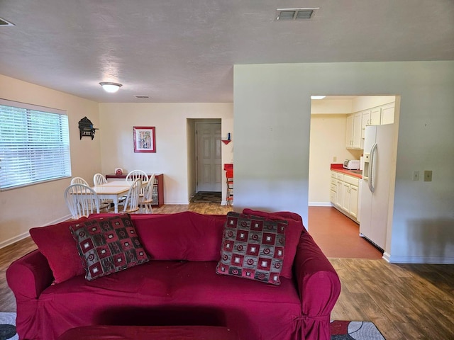 living room featuring baseboards, wood finished floors, and visible vents