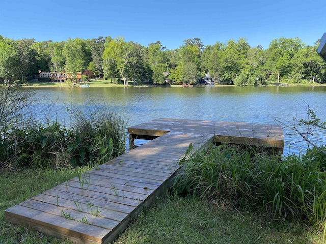 view of dock with a wooded view and a water view