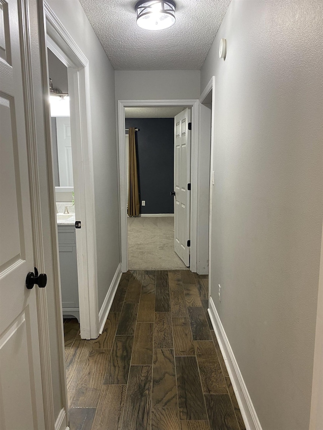 hall featuring dark wood-type flooring, sink, and a textured ceiling