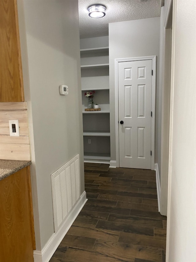 corridor with dark wood-type flooring and a textured ceiling