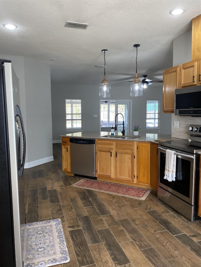 kitchen with appliances with stainless steel finishes, sink, a textured ceiling, and kitchen peninsula