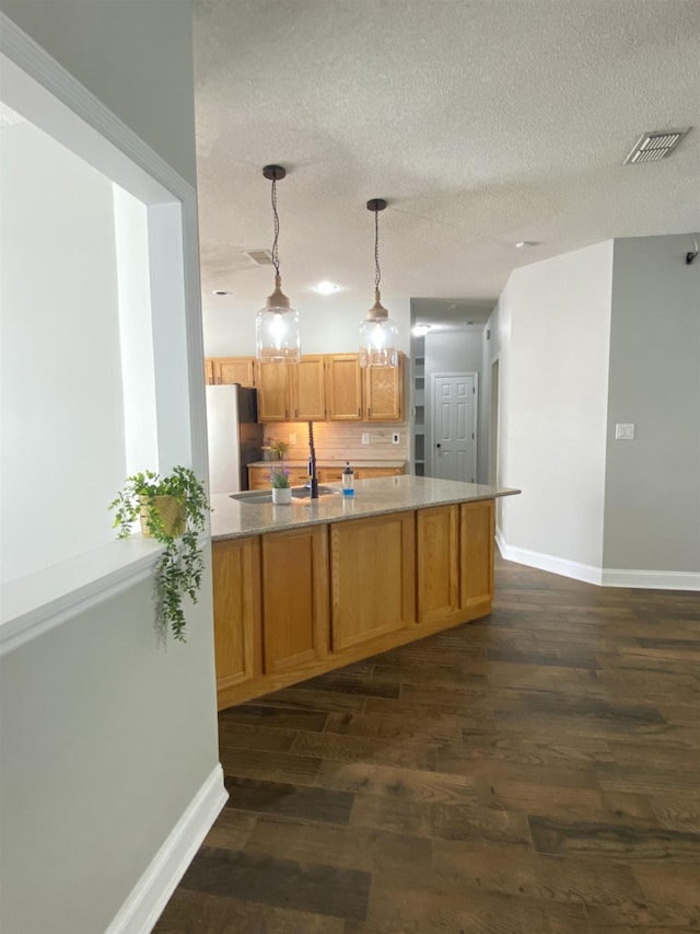 kitchen featuring pendant lighting, stainless steel fridge, decorative backsplash, dark wood-type flooring, and a textured ceiling