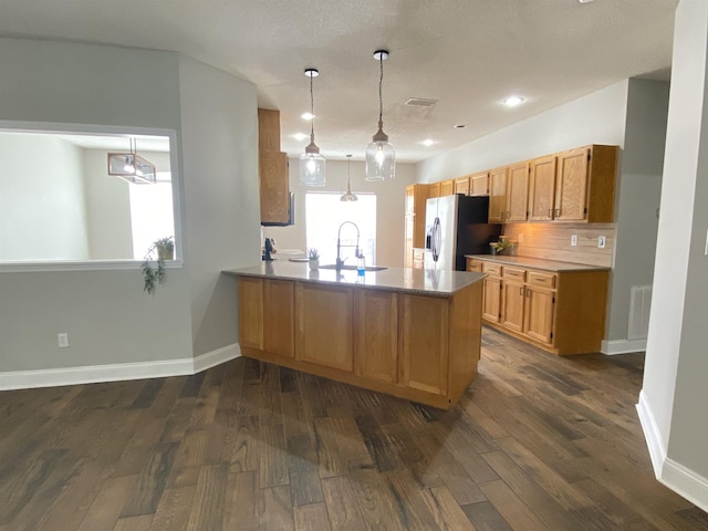 kitchen with decorative light fixtures, sink, stainless steel fridge, dark hardwood / wood-style flooring, and kitchen peninsula