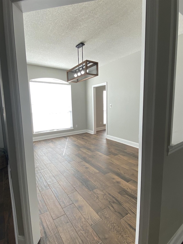 unfurnished dining area with dark hardwood / wood-style flooring and a textured ceiling