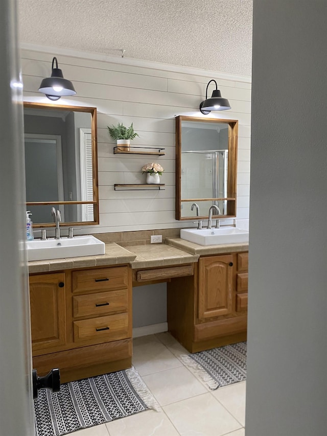 bathroom featuring vanity, a shower with door, tile patterned flooring, and a textured ceiling