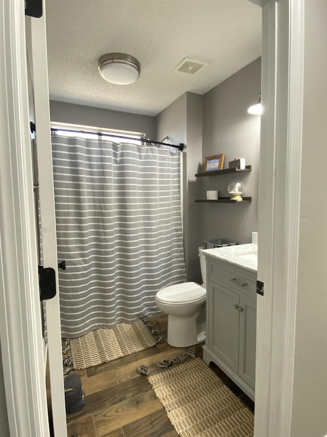 bathroom with hardwood / wood-style floors, vanity, toilet, a textured ceiling, and a shower with curtain