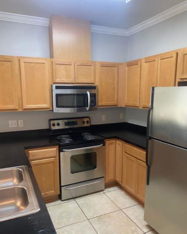 1417 Pullen Rd Unit 101, Tallahassee, FL 32303 - kitchen with stainless steel appliances, ornamental molding, light tile patterned floors, light brown cabinetry, and dark countertops