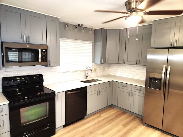 kitchen featuring a sink, decorative backsplash, stainless steel appliances, light countertops, and gray cabinetry