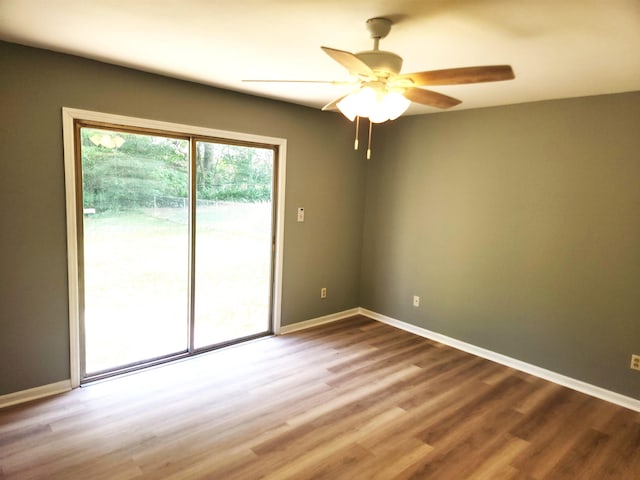 empty room featuring baseboards, wood finished floors, and ceiling fan
