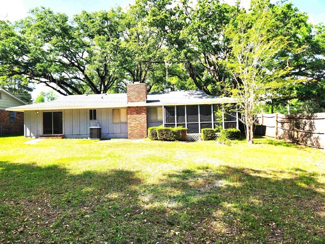 back of property featuring central AC, a chimney, board and batten siding, fence, and a sunroom