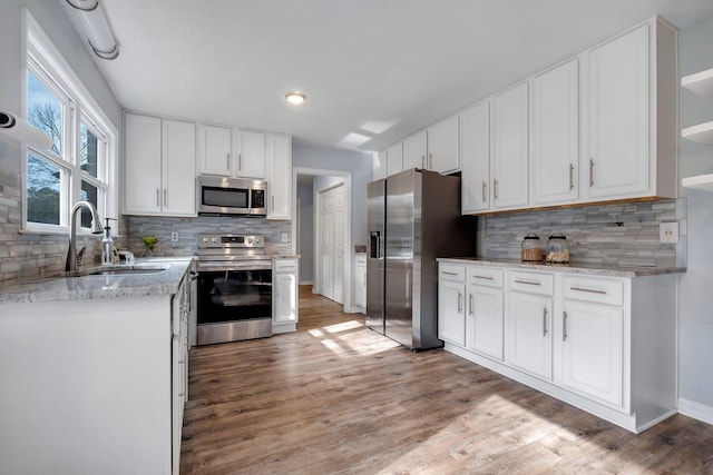 kitchen featuring appliances with stainless steel finishes, sink, white cabinetry, and light hardwood / wood-style flooring