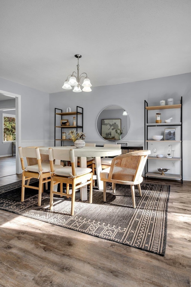 dining space featuring wood-type flooring and a notable chandelier