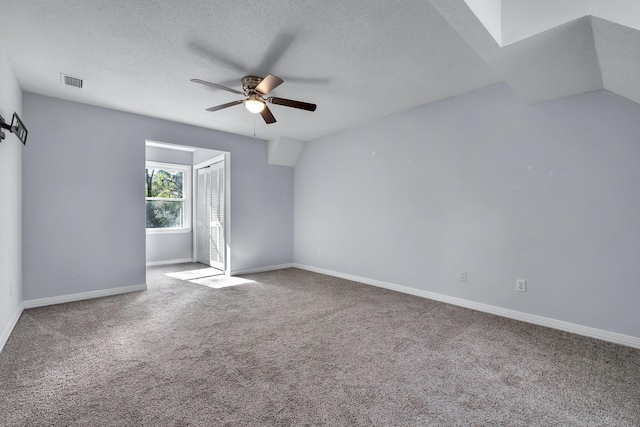 interior space featuring a textured ceiling, ceiling fan, carpet flooring, and lofted ceiling