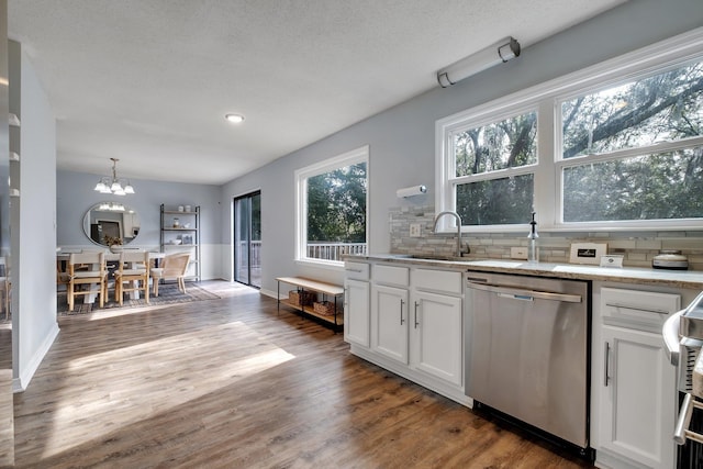 kitchen with pendant lighting, white cabinetry, tasteful backsplash, sink, and stainless steel dishwasher