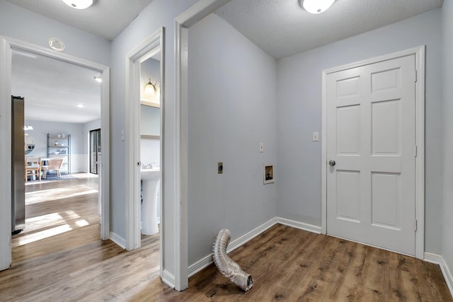 washroom featuring hookup for a washing machine, wood-type flooring, a textured ceiling, and hookup for an electric dryer