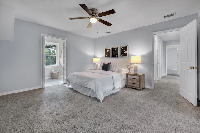 carpeted bedroom featuring a textured ceiling, ceiling fan, and ensuite bath